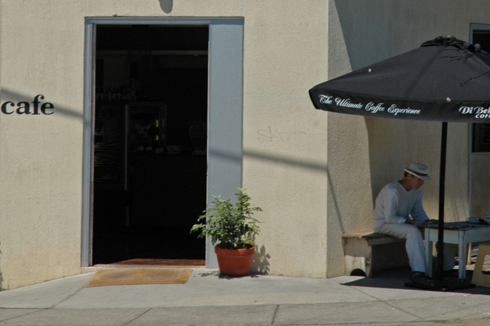Man sitting wearing panama hat outside Brown Dog Cafe
