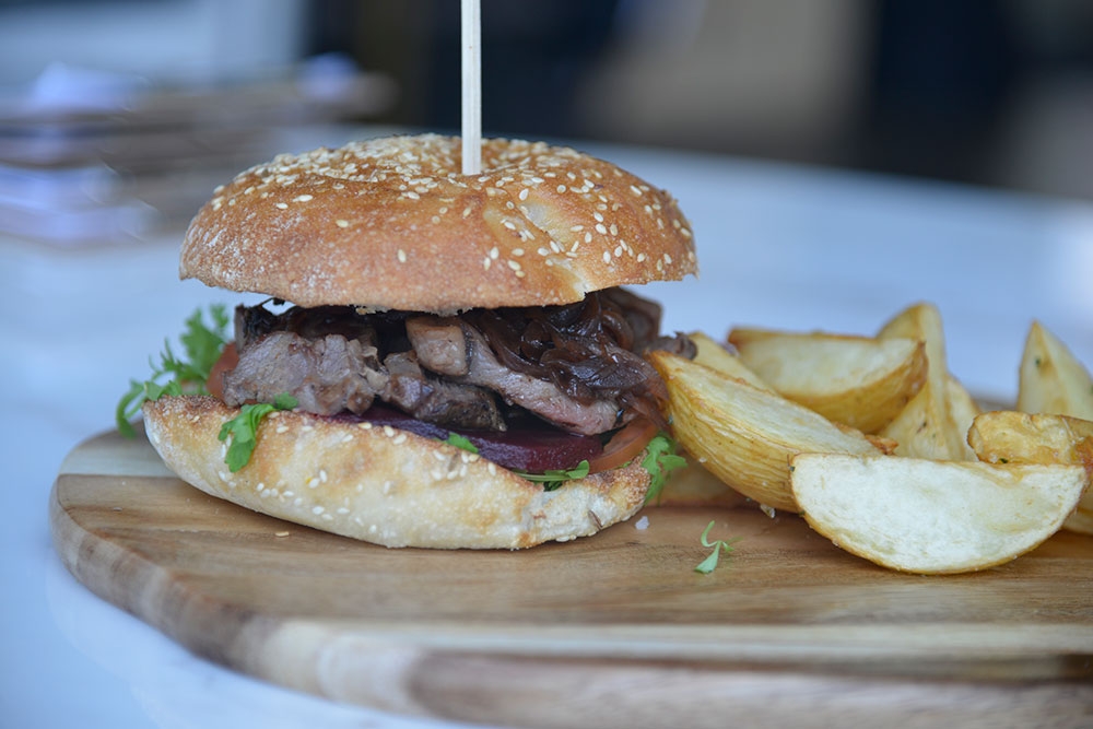Steak burger in a bun with fries