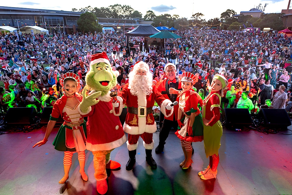Crowd watching characters on stage Christmas Carols Logan