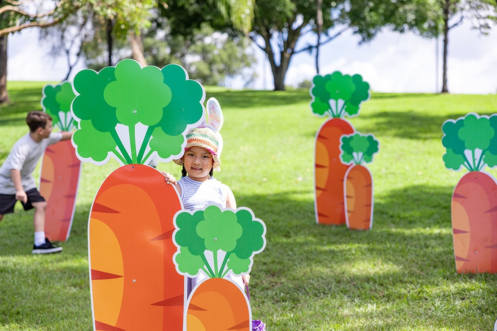 Child standing behind a decorative carrot at Easter Weekend at Roma Street Parkland