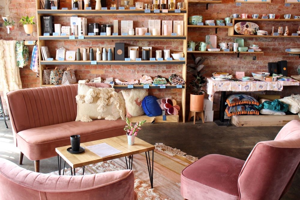 Blush pink velvet lounge and matching chairs with shelves on walls stocked with products at Corn Street, Ashgrove