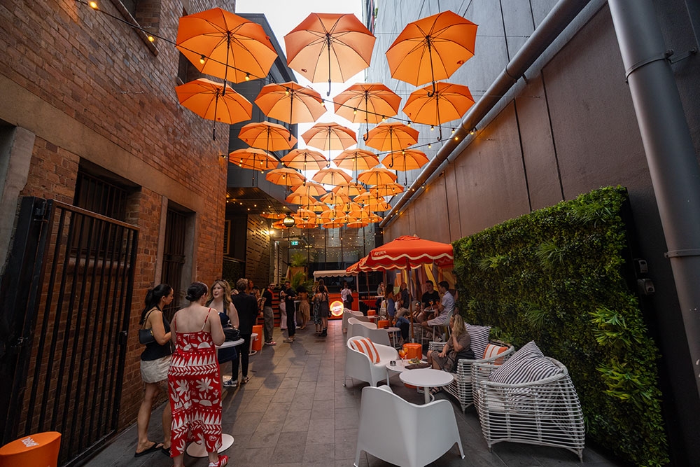 People seated under orange umbrellas in Doughcraft Lane