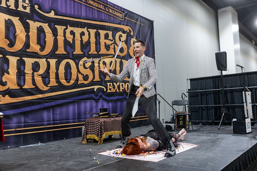 Man on stage juggling knives at the Oddities & Curiosities Expo