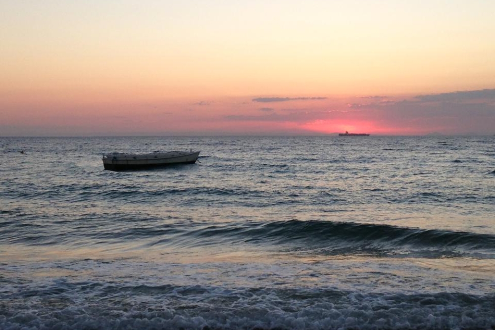 Sunset with lone rowing boat in ocean at the Glamping at Castaways resprt on Moreton Island