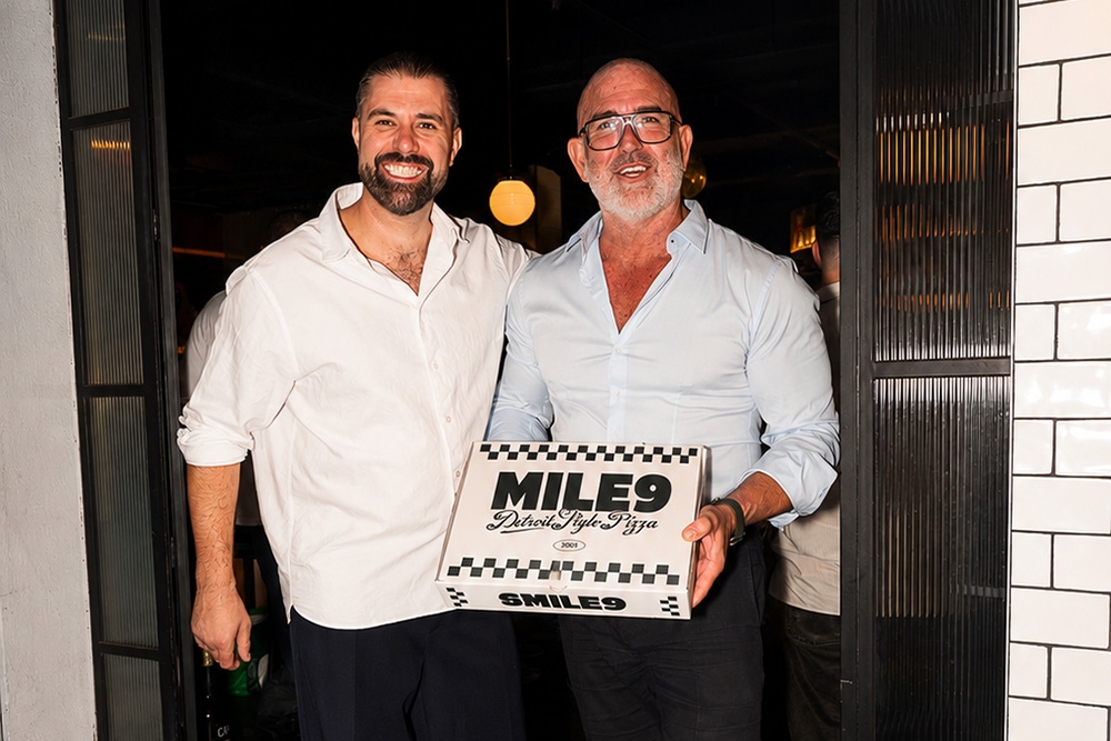 Two people with a Mile9 pizza
