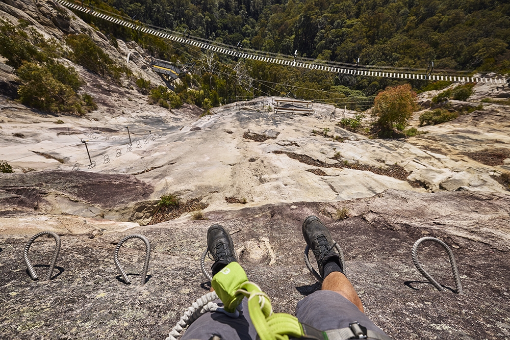 Boots on a cliff on The Arête Via Ferrata Tour at the Happitat Adventure Park