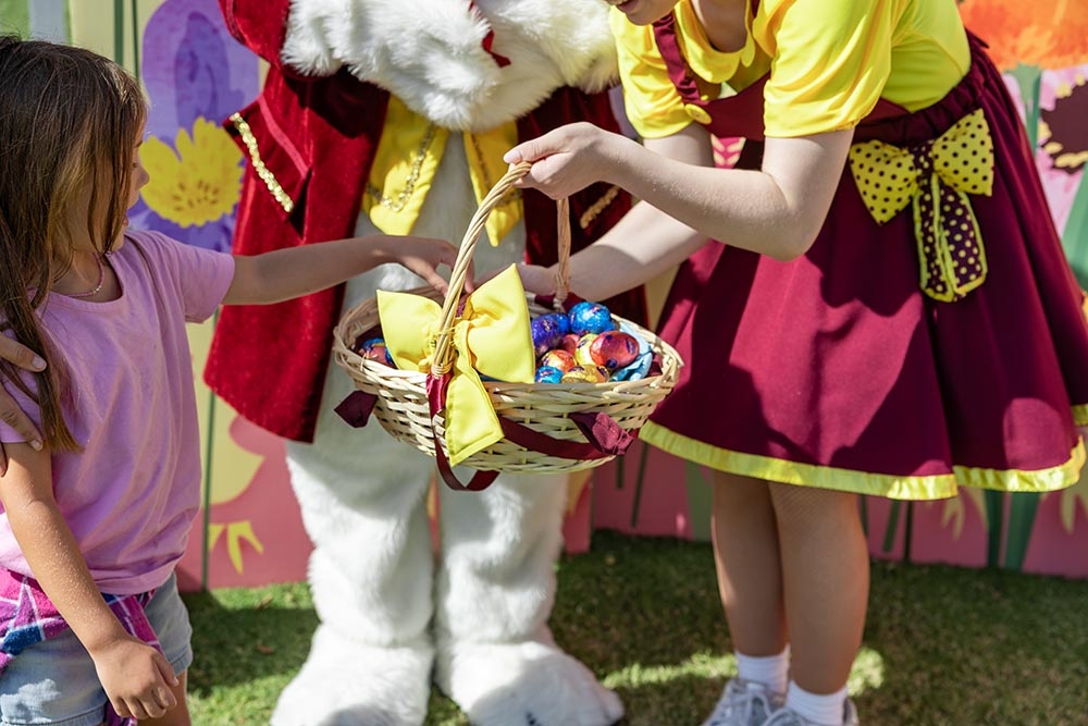 Child getting handed an Easter egg at the Easter Weekend at Roma Street Parkland