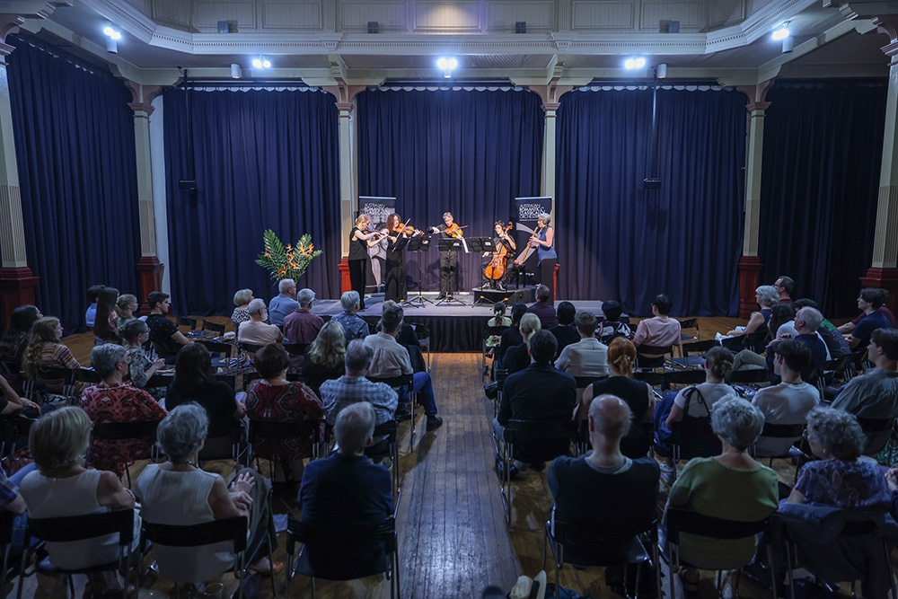 ARCO Orchestra performing on stage with crowd watching