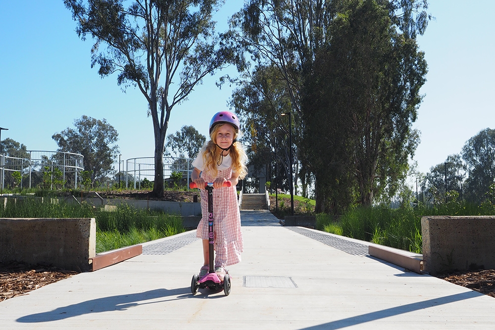 Girl riding scooter on pathyway Archerfield Wetlands District Park