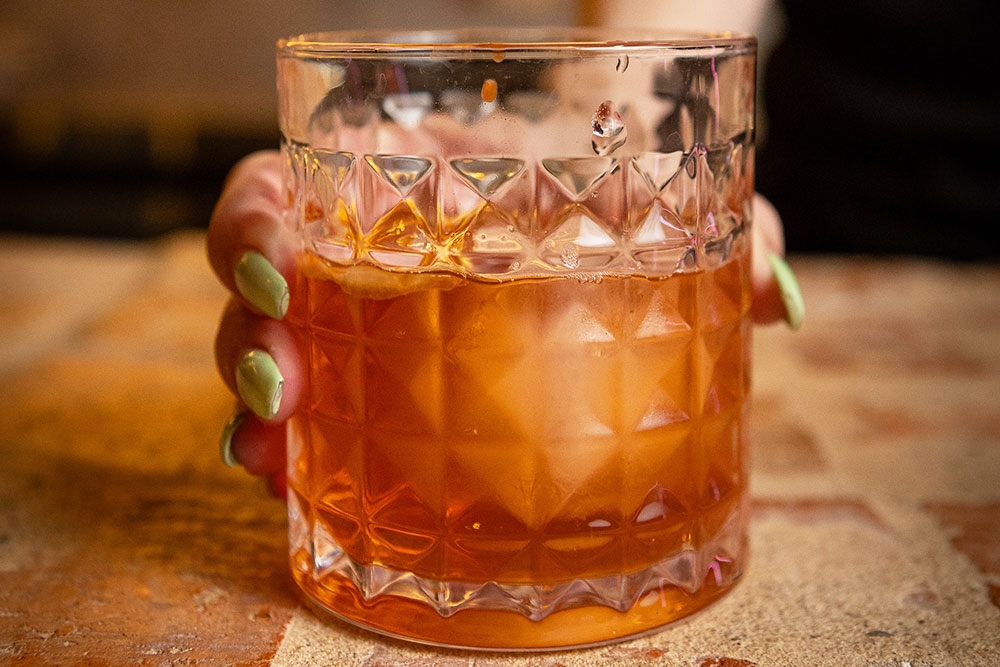 Glass of alcohol being held by a hand at Bar Mesopotamia Milton