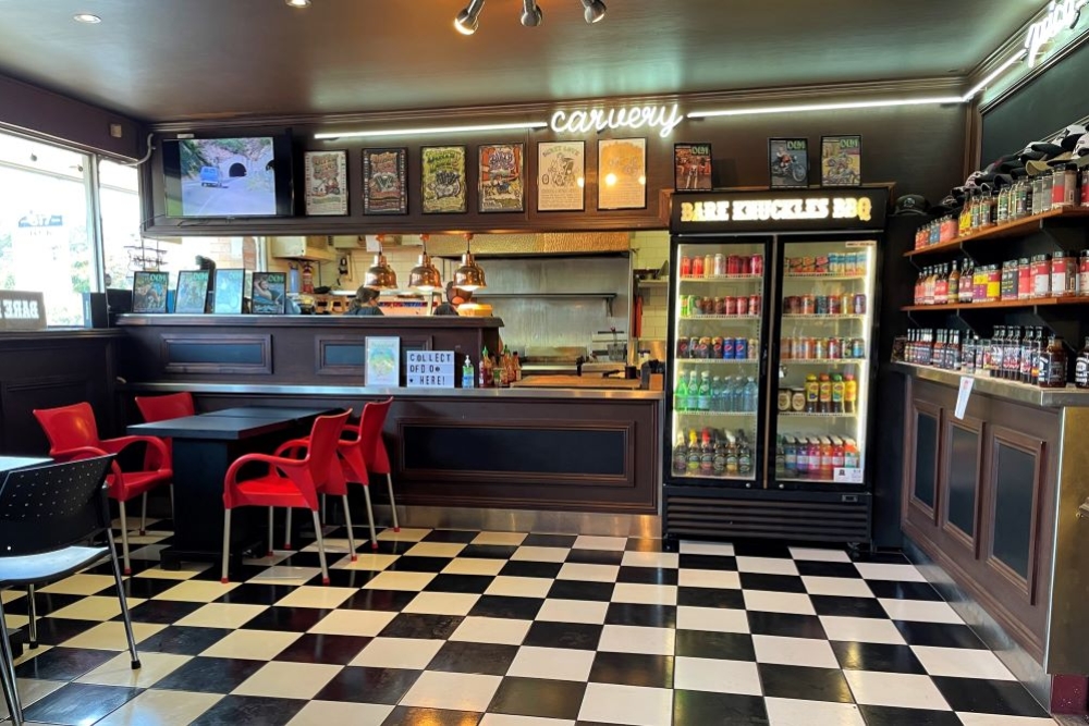 Counter, drinks fridge and table on checkerboard floor inside Bare Knuckles BBQ, Salisbury