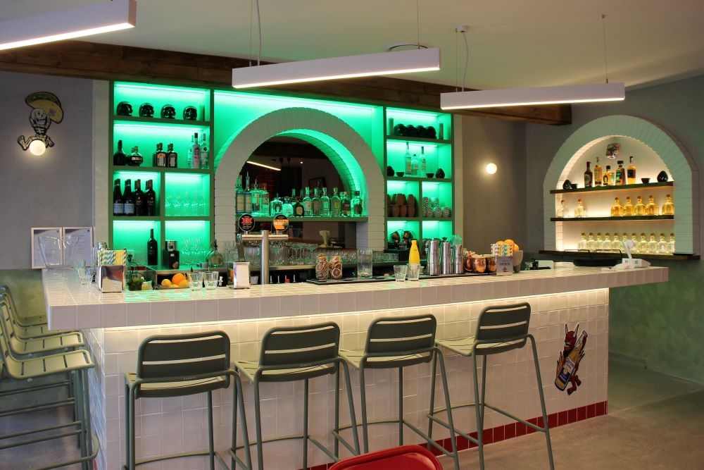 Green-lit bar at night inside Cartel Del Taco, Hawthorne 