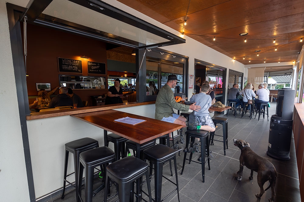 People sitting on bar stools outside at Clover Neighbourhood Bar Holland Park