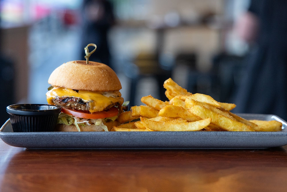 Burger and fries on a plate at Clover Neighbourhood Bar Holland Park