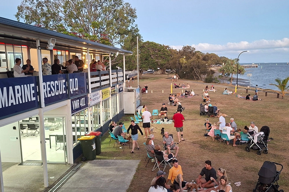 Crowd of people on lawn out front of The Deck Bar