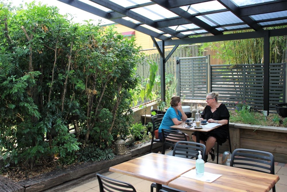 People sitting at alfresco dining area inside shaded courtyard at Dovetail Social, Highgate Hill 