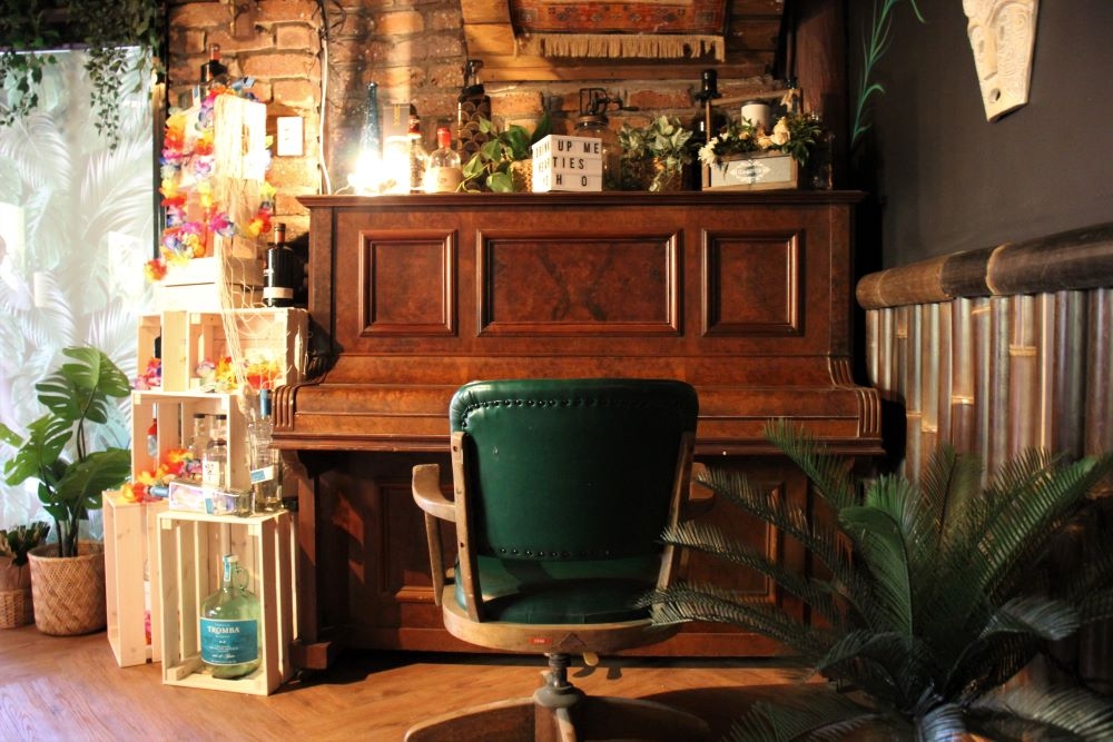 Piano, green office chair  and wooden decorative crates inside The Fourth Monkey Bar, West End 