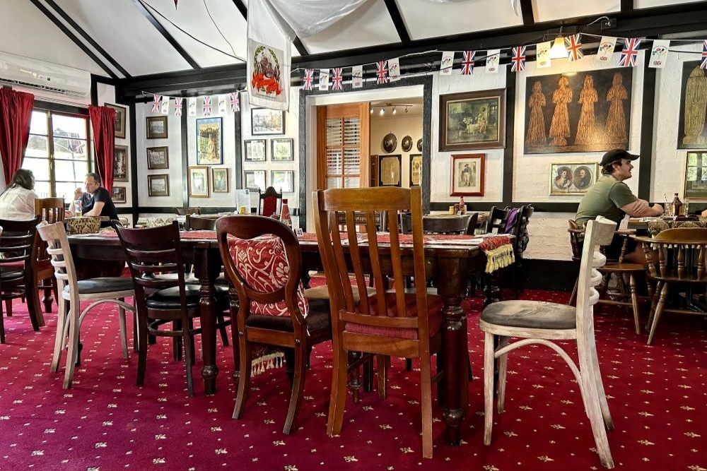 Mismatched chairs and tables with British memorabilia on the walls inside Fox & Hounds Country Inn, Wongawallan