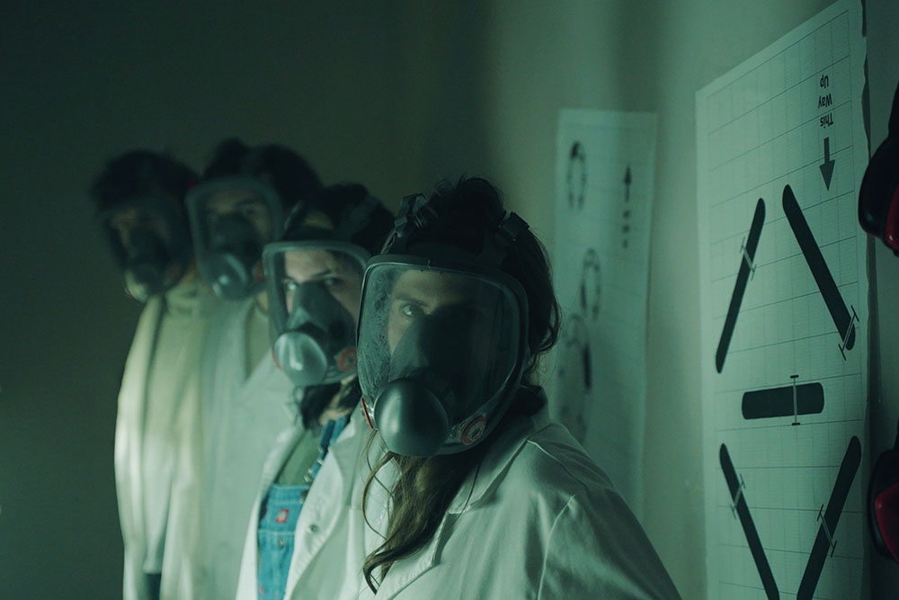 Four people wearing gas masks and white coats at Project Immersive's Area 1 Escape Rooms
