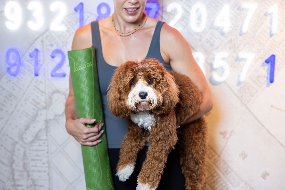 Woman holding puppy and yoga mat