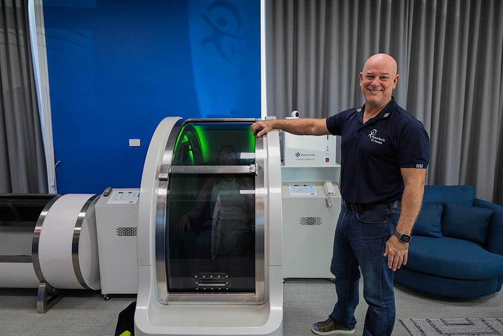 Matt poses in front of the Hyperbaric chamber 