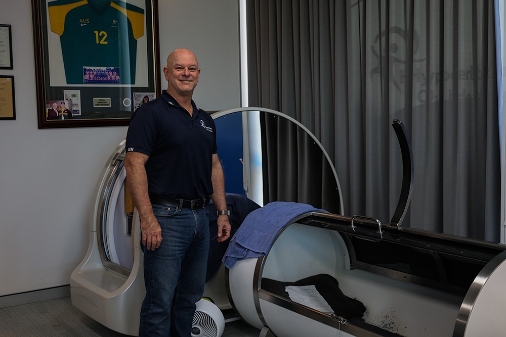 Matt poses in front of the Hyperbaric chamber 