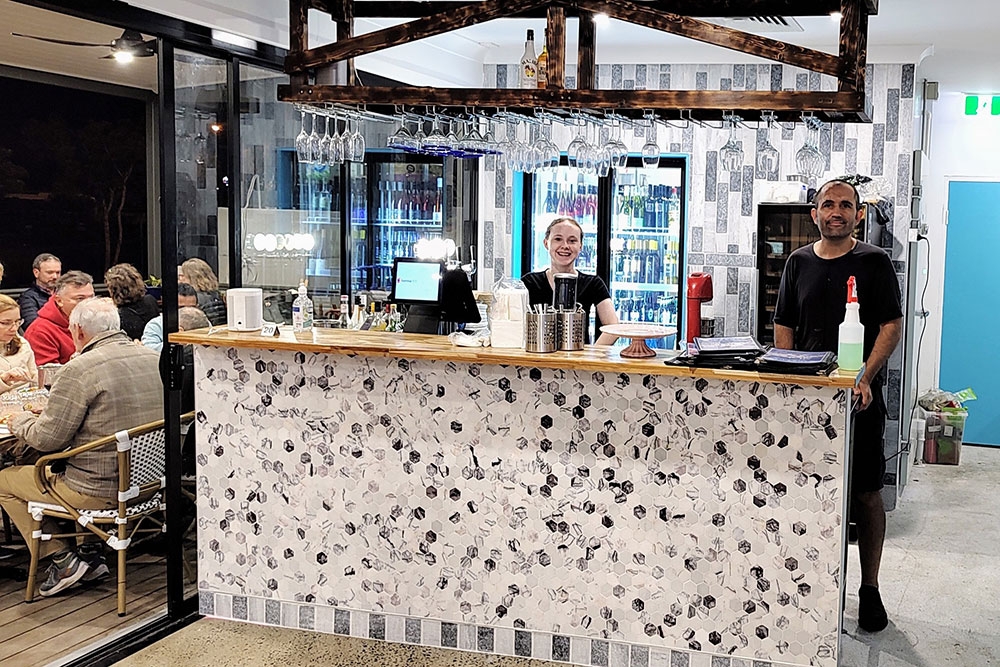 Two staff standing behind bar at Icarus Restaurant Jindalee