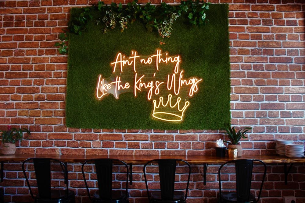 Wall with neon sign and seating inside King of the Wings, Stafford