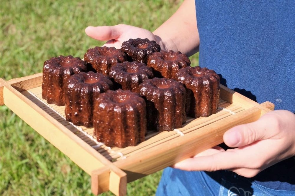 Hands carrying wooden tray of brown desserts at Mountain River Patisserie Runcorn