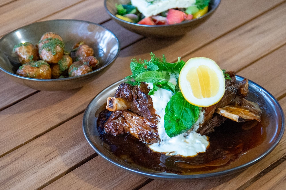 Dishes of Greek lamb, potatoes and salad on table Mede restaurant Bulimba