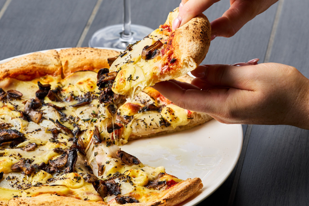 Plate of pizza with hands grabbing a slice 