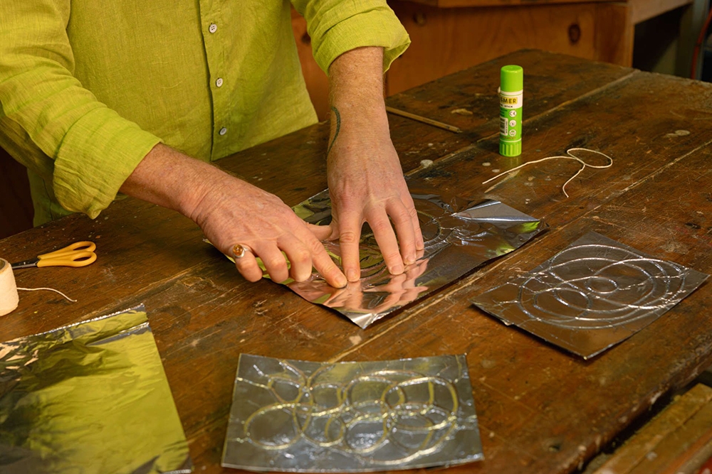 Artist making works from foil string & glue