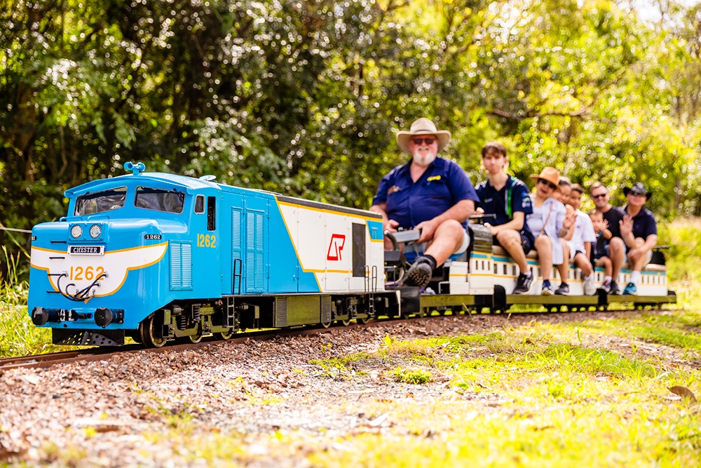 Miniature steam engine with people aboard it at Planes, Trains And Autos 2026