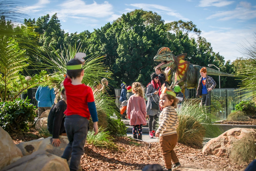 Children outside playing around dinosaur display