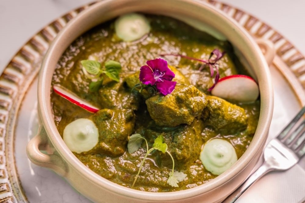 Bowl of curry with a pink flower on top at New Farm Curry House 