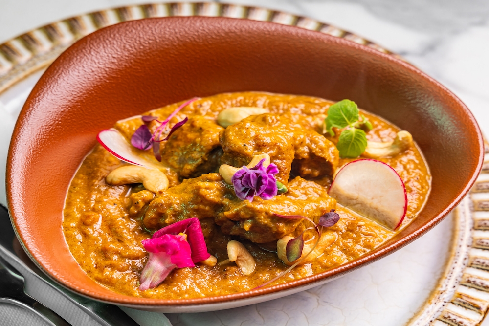 Bowl of curry with pink flowers on top at New Farm Curry House 