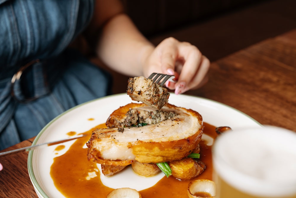 Person eating meat with a fork at Newnham Hotel Mount Gravatt 