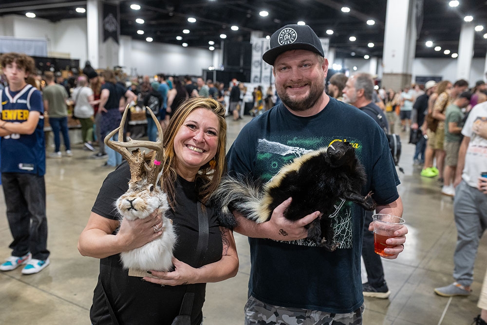 Man and woman holding taxidermy animals at the Oddities & Curiosities Expo