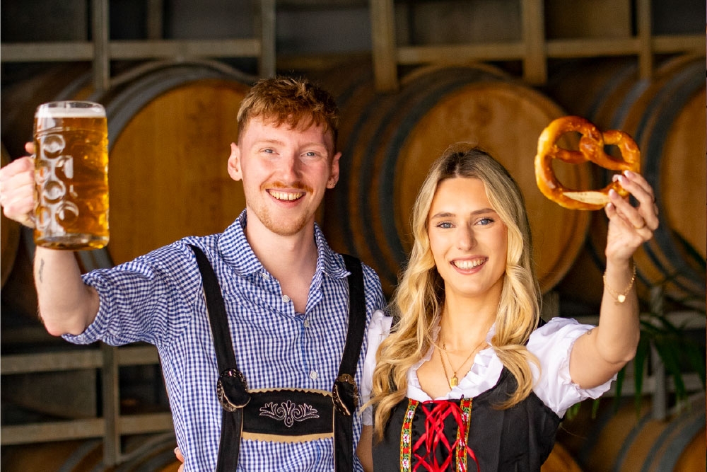 Couple holding beer & pretzel at Oktoberfest at The Hills