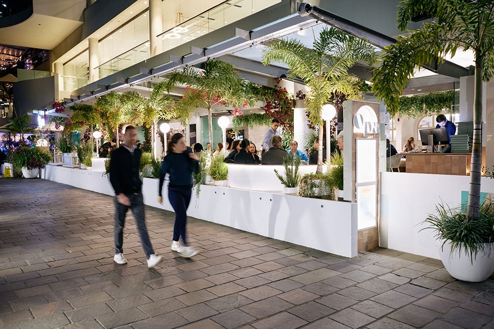 Man and woman walking passed Opa Bar & Mezze at night