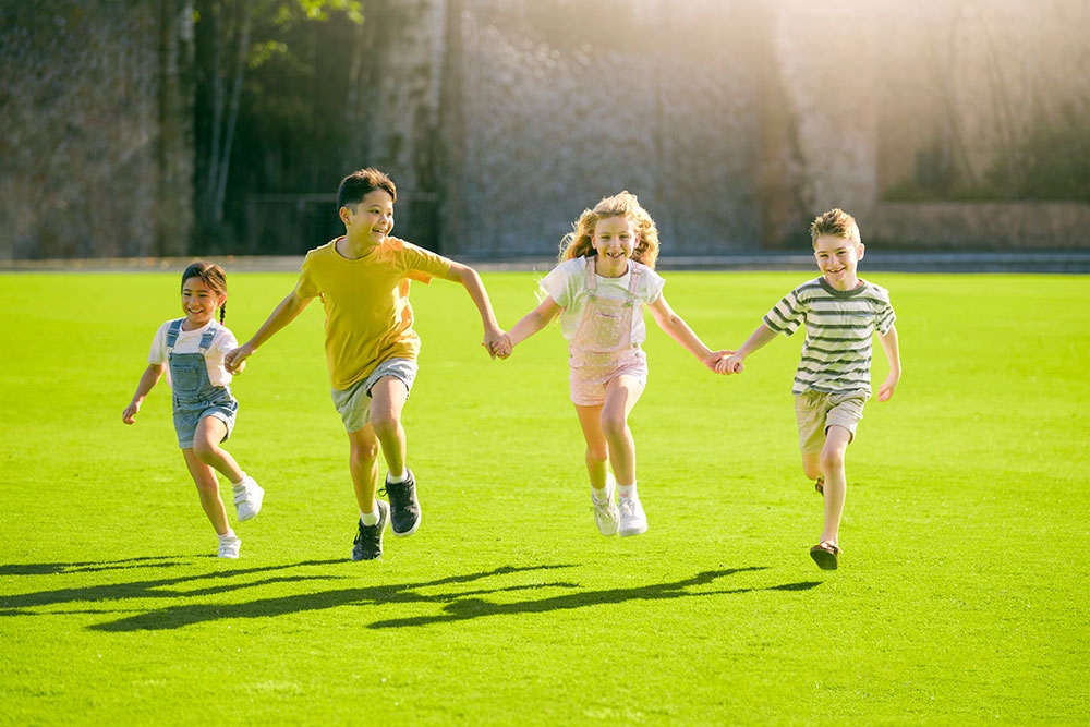 Four children holding hands and skipping at Playtopia, Roma Street Parkland 