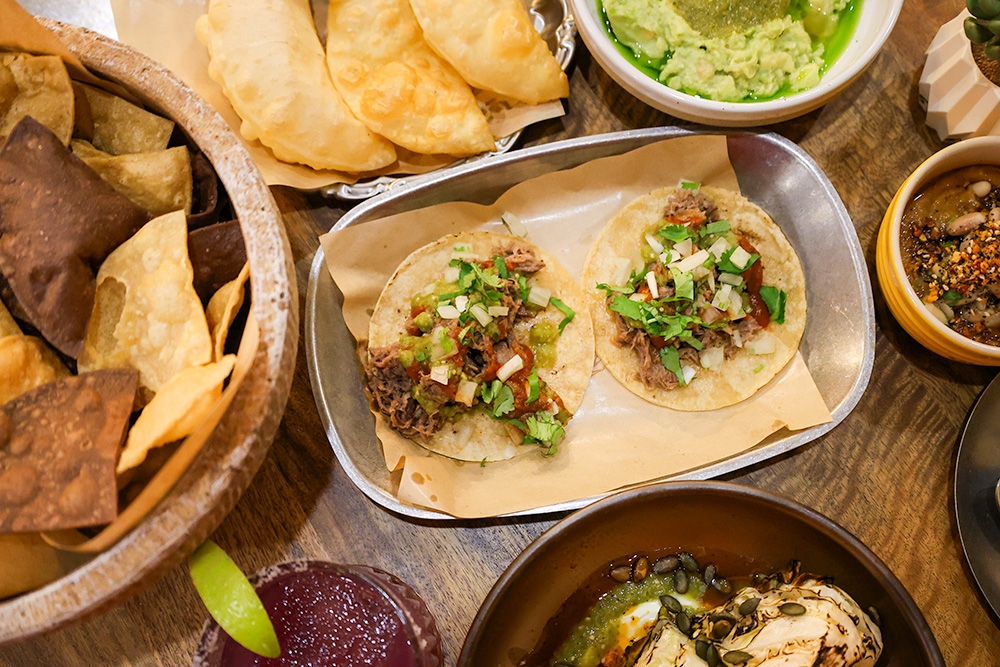Plates of tacos, dips and chips on a table