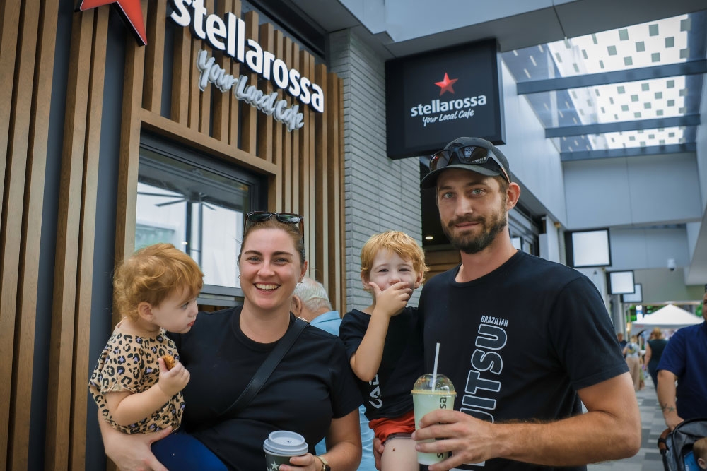 Family in food court holding drinks and children