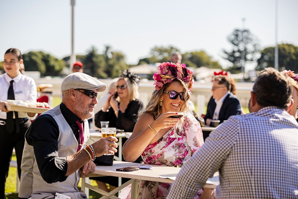 People in the crowd sitting at a table drinking at Stradbroke Season 2026