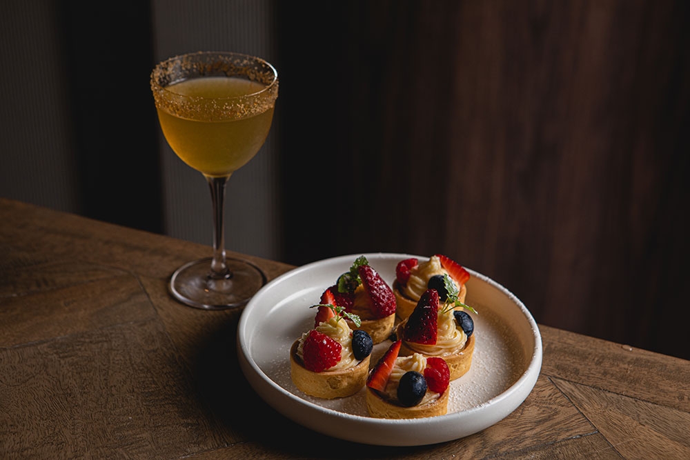 Four custard mini tarts in a plate with a glass of wine at South City Wine Bar Woolloongabba