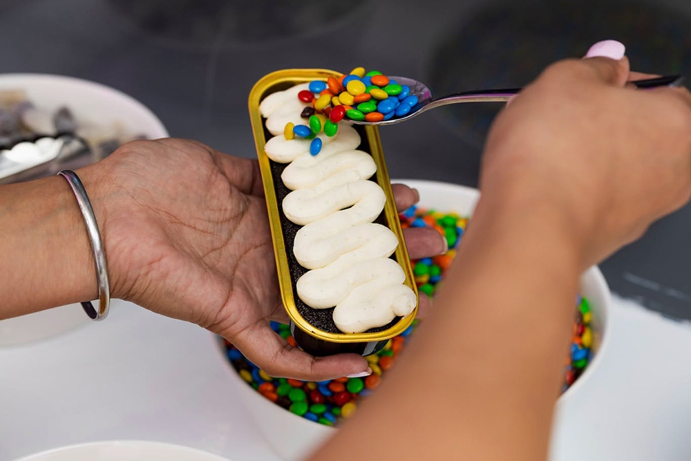 person putting topping on cake