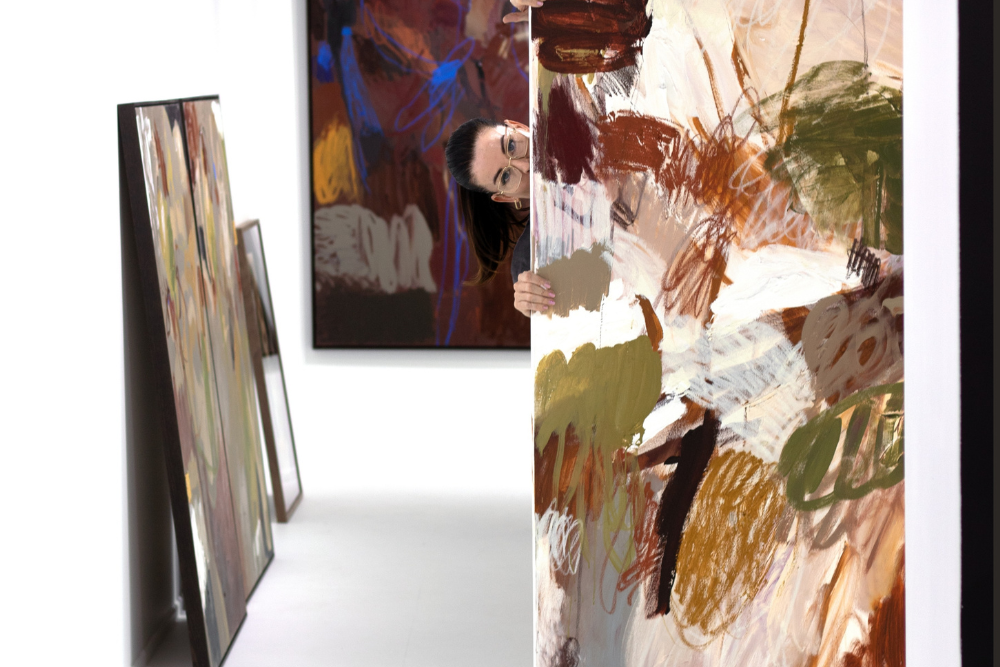 women poking head around corner of painting 