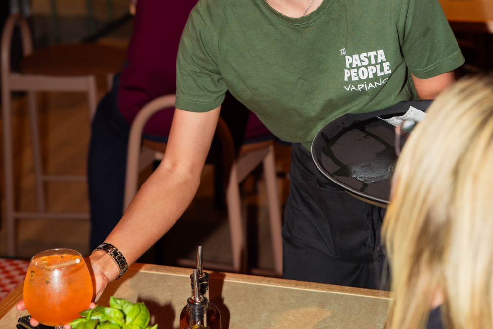 Staff member putting cocktail on table at Vapiano Italian Restaurant, Ipswich