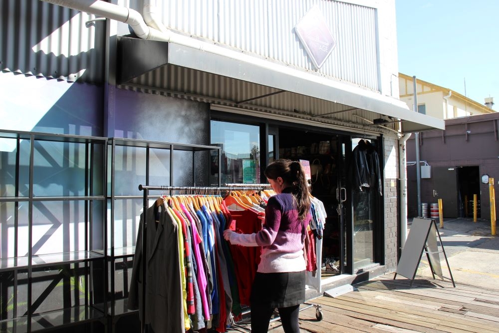 Woman looking through rack of clothing outside Vintage Street, Stones Corner 