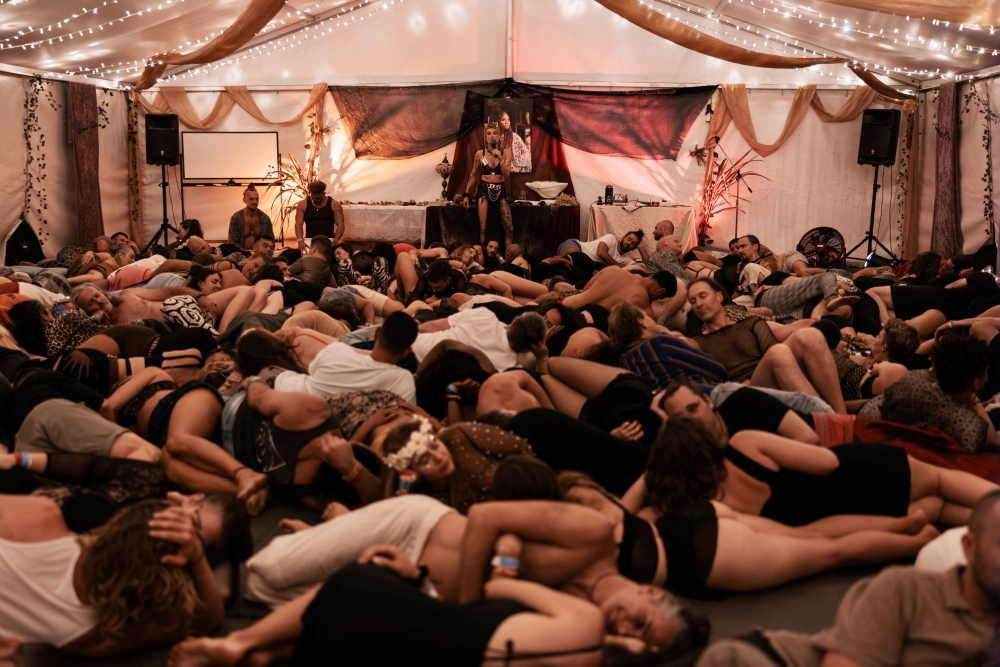 people lying down in a tent with a lady talking into a mic 